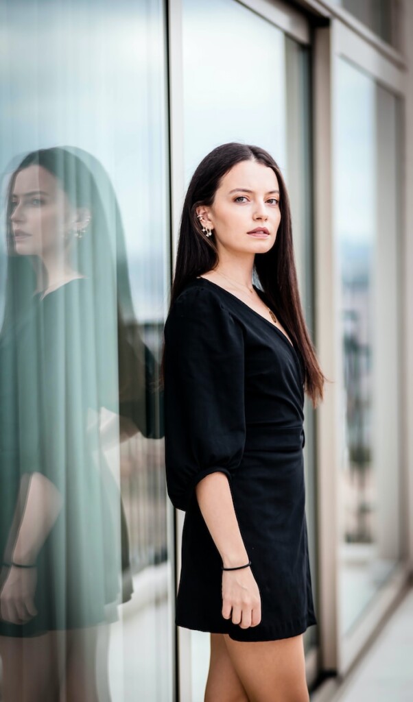 woman in black long sleeve shirt standing beside glass window