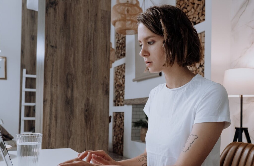 Woman in White Crew Neck T-shirt Using Macbook Air