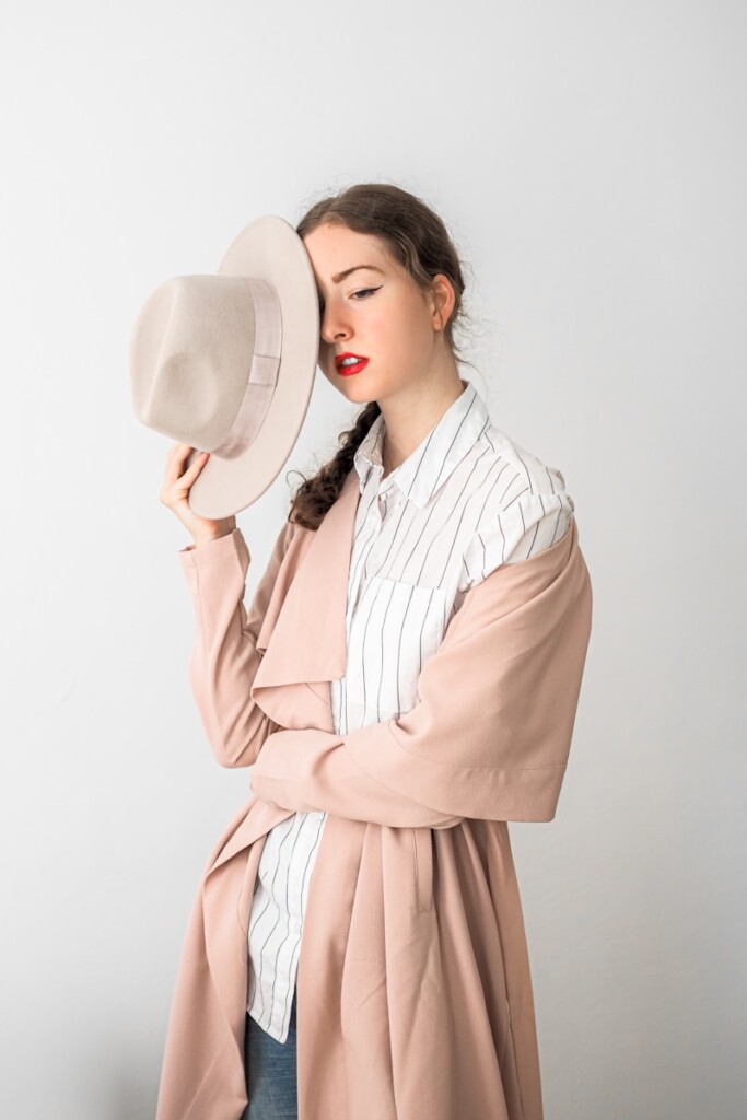 a woman holding a hat up to her face