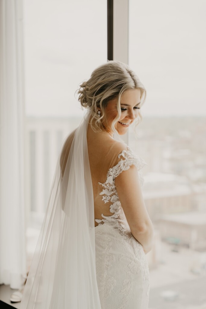 a woman in a wedding dress looking out a window